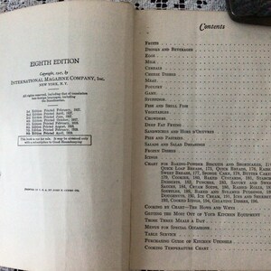 May include: A vintage cookbook titled "Eighth Edition" by International Magazine Company, Inc. The book lists various recipes and cooking techniques, including baking, desserts, and frozen dishes.