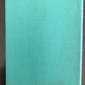 Puede incluir: Un libro de tapa dura rectangular con una cubierta de tela lisa de color verde azulado. El libro presenta una textura simple y uniforme en toda la superficie frontal, sin texto, ilustraciones ni marcas visibles en el exterior de la encuadernaci&oacute;n.