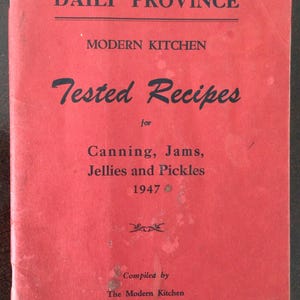 May include: A red vintage booklet titled The Vancouver Daily Province Modern Kitchen Tested Recipes for Canning, Jams, Jellies and Pickles 1947. The cover features black text, a small decorative graphic, and states it was compiled by The Modern Kitchen.