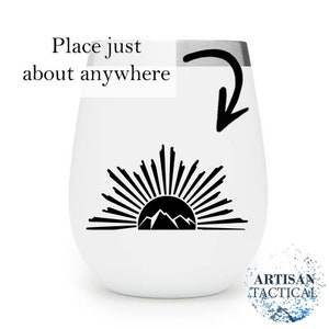 Puede incluir: Un vaso de vino blanco de acero inoxidable con una silueta negra de una cordillera y un dise&ntilde;o de sol naciente. El texto "Place just about anywhere" est&aacute; escrito sobre el dise&ntilde;o.