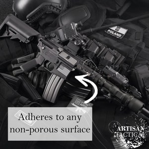 Puede incluir: Una linterna t&aacute;ctica negra con un agarre texturizado y un anillo de metal. La linterna est&aacute; unida a un rifle negro con una pegatina de bandera estadounidense en blanco y negro. El texto "SPECNA ARMS" es visible en un parche negro.