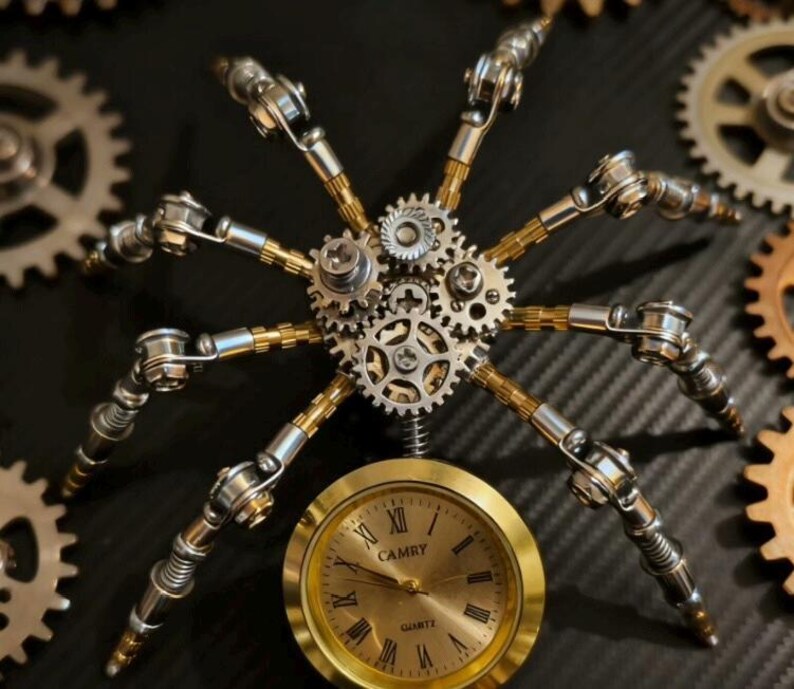 Pu&ograve; includere: Scultura a forma di ragno in metallo in stile steampunk con ingranaggi e un quadrante dorato. Le zampe del ragno sono in metallo argentato e ottone. Il quadrante dell'orologio indica "CAMRY Quartz" con numeri romani.