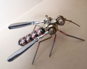 May include: A steampunk-style insect sculpture made of metal. The insect has a black and copper body with silver wings and legs. The insect is posed with its wings spread out.