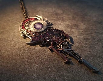 May include: A silver and bronze key pendant necklace with a clock face and intricate details. The clock face has a purple and white design.