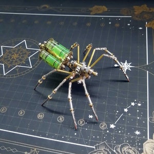 May include: A steampunk-style spider made of metal with a green and gold color scheme. The spider has eight legs and a body with intricate details. The spider is posed on a black surface with a grid pattern.