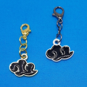May include: Two black cloud charms with gold and silver chains. The charms are attached to a lobster clasp.