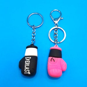 May include: Two boxing glove keychains, one black with the word "EVERLAST" on it and one pink. Both keychains have silver key rings.