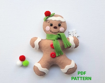 May include: A felt gingerbread man ornament with a green scarf, white icing, and red buttons. The ornament is holding a white snowflake. The text "PDF PATTERN" is visible in the bottom right corner of the image.