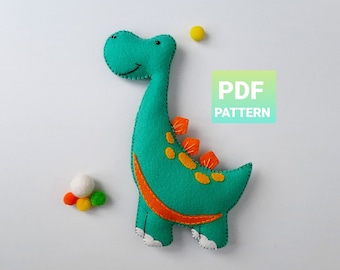 May include: A PDF pattern for sewing a felt dinosaur toy. The dinosaur is green with orange accents and white stitching. The pattern includes instructions for making the toy.