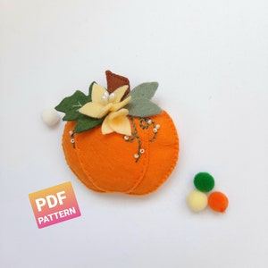 Op de afbeelding: Een patroon voor een viltpompoen met een gele bloem en groene bladeren. Het patroon bevat instructies voor het maken van een viltpompoen met een bloem en bladeren. Het patroon is beschikbaar als PDF-download.