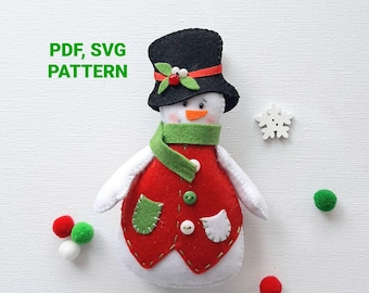 May include: A felt snowman ornament with a black top hat, red jacket, green scarf, and white buttons. The ornament is on a white background with a snowflake and green and red pom-poms.