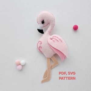 May include: A pink felt flamingo with a black beak and tan legs. The flamingo has pink wings and decorative stitching. The image also includes three small pom-poms and the text "PDF, SVG PATTERN".