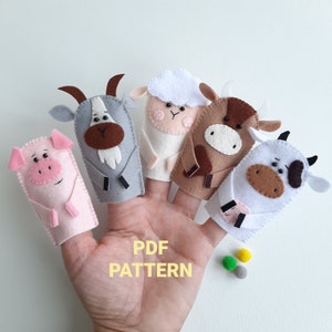 May include: Five felt finger puppets of farm animals: a pig, goat, sheep, cow, and a cow with black and white spots. The puppets are on a hand with the text "PDF PATTERN" below.