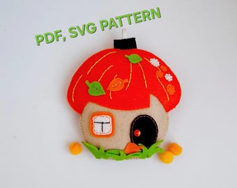 May include: A felt craft ornament shaped like a house with a bright orange mushroom-style roof, a beige base, a small window, and a black door. The text PDF, SVG PATTERN is visible above the ornament, which is decorated with green and orange felt leaves.