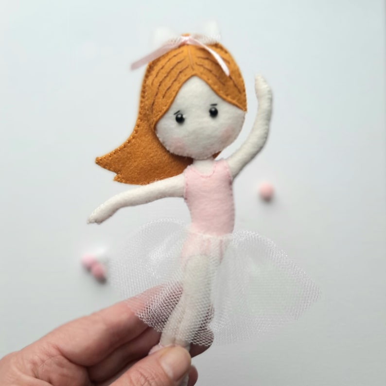 May include: A felt ballerina doll with brown hair, a pink leotard, and a white tulle skirt.