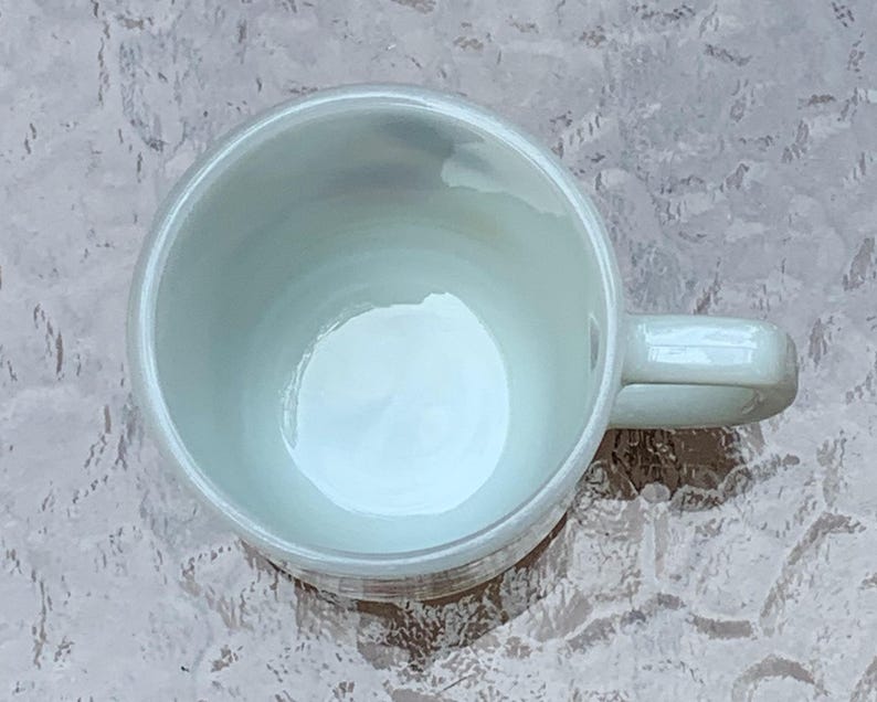 May include: A white ceramic coffee mug with a handle. The mug is empty and has a smooth, glossy finish.