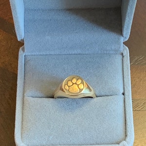 May include: A gold ring with a paw print design in a blue velvet ring box.