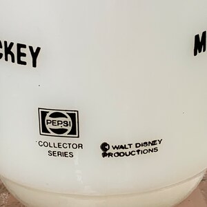 May include: White ceramic Mickey Mouse mug with black lettering and a Pepsi logo. The mug is part of a collector series and features the Walt Disney Productions logo.