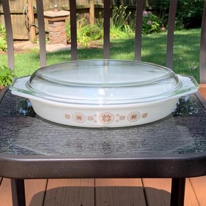 May include: White oval casserole dish with a clear glass lid. The dish has a brown and white floral pattern around the edge.