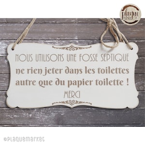 Peut inclure: Une pancarte en bois blanc avec du texte brun qui dit "NOUS UTILISONS UNE FOSSE SEPTIQUE ne rien jeter dans les toilettes autre que du papier toilette ! MERCI". La pancarte est suspendue à une corde et a un fond en bois rustique.