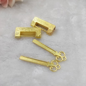 May include: Gold-coloured decorative locks and keys. Two rectangular locks with floral designs are displayed with two matching keys. The keys have ornate, scrolled handles. The items are arranged on a soft, white surface.