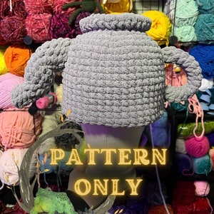 Op de afbeelding: Een grijze gehaakte trui met een hoge hals en een lange mouw. De trui wordt getoond op een mannequin en is omringd door bollen garen. De tekst "PATTERN ONLY" is over de afbeelding gelegd.