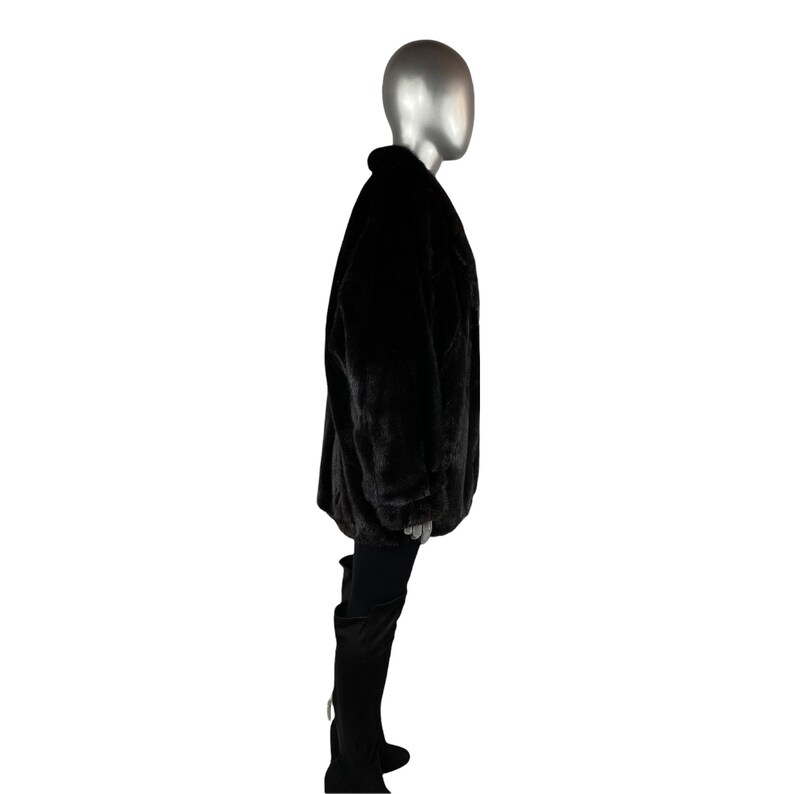 K&ouml;nnte beinhalten: Eine schwarze Kunstfelljacke mit langer, lockerer Passform. Die Jacke hat einen Kragen und lange &Auml;rmel.