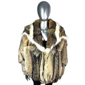 May include: A vintage fur coat with a mix of brown, tan, and white fur. The coat features a wide collar and a zip-up front. The sleeves have a patterned fabric detail at the cuffs. The coat is displayed on a mannequin.