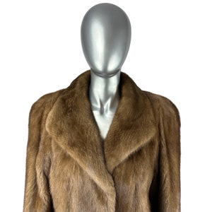 May include: A brown fur coat with a large collar. The coat is on a mannequin.