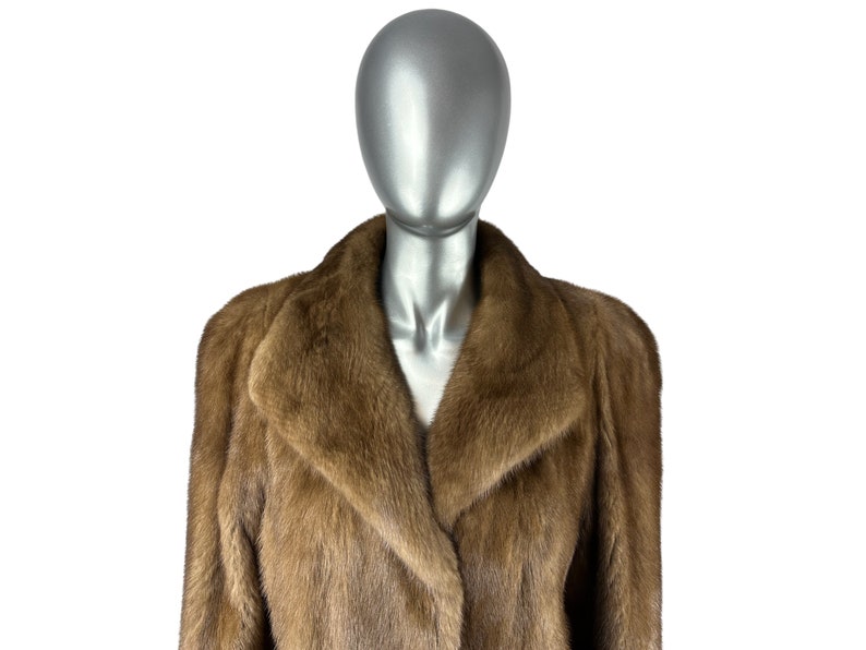 May include: A brown fur coat with a large collar. The coat is on a mannequin.