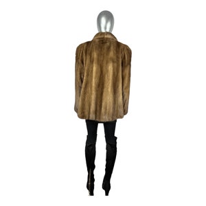 May include: A brown fur coat with a stand-up collar. The coat is worn on a mannequin.