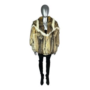 May include: A full-length shot of a mannequin wearing a fur coat. The coat is a mix of brown, tan, and cream colors. It has a wide collar and a zipper closure. The mannequin is also wearing a black skirt and black thigh-high boots.