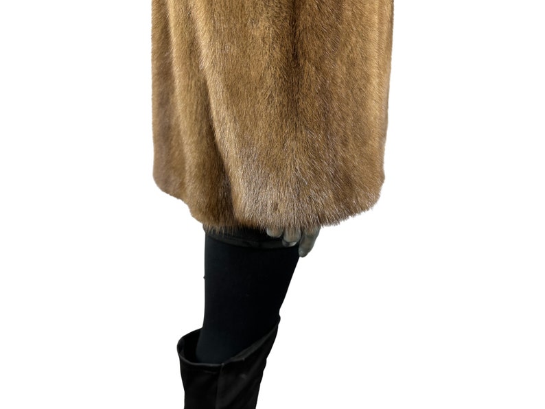 May include: A brown fur coat with a long sleeve and a soft, fluffy texture.