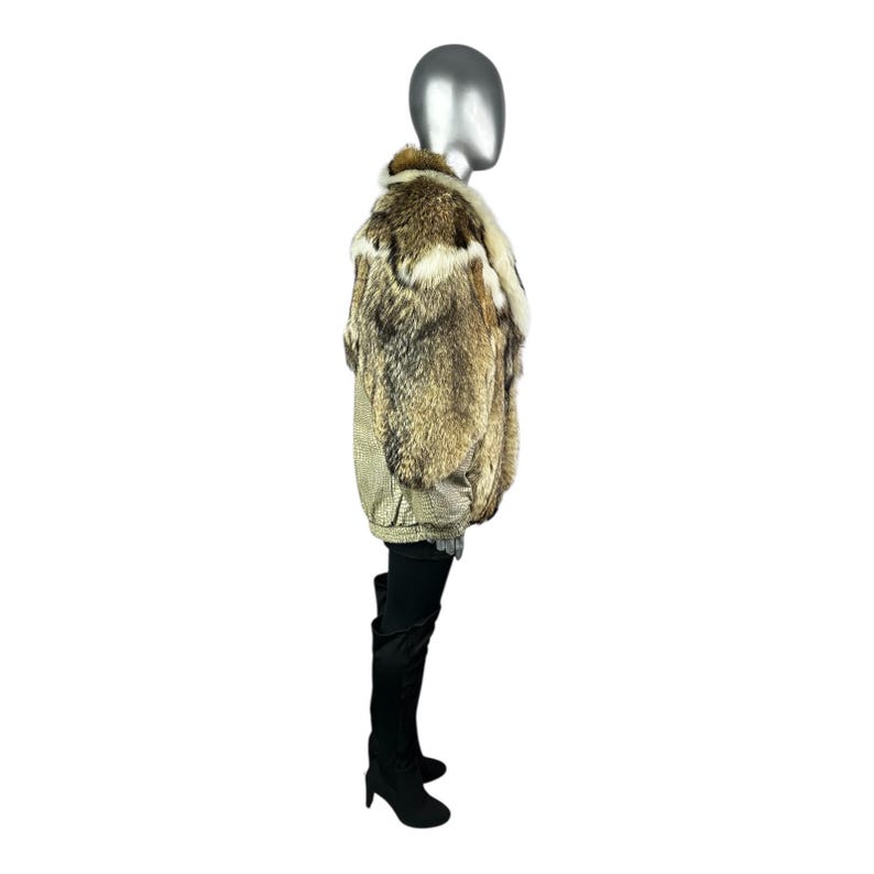 May include: A fur coat with a mix of brown, tan, and white fur. The coat has a collar and a patterned lining. The mannequin is wearing black thigh-high boots.