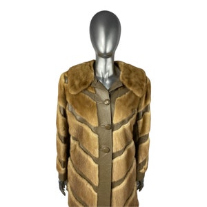 May include: A long brown fur coat with leather panels and a button closure. The coat has a large collar and is made of a soft, luxurious fur.