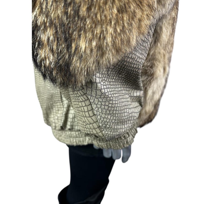 May include: A jacket with a faux fur collar and a textured, reptile-like pattern on the sleeves and body. The jacket features a mix of brown, tan, and black colors, creating a luxurious look. The sleeves are gathered at the wrist.