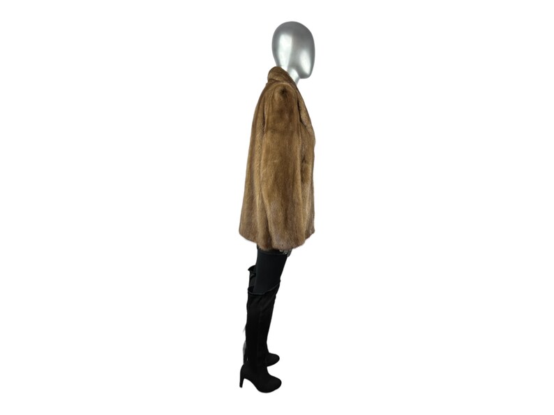 May include: A brown faux fur jacket with a collar and long sleeves. The jacket is worn on a mannequin.
