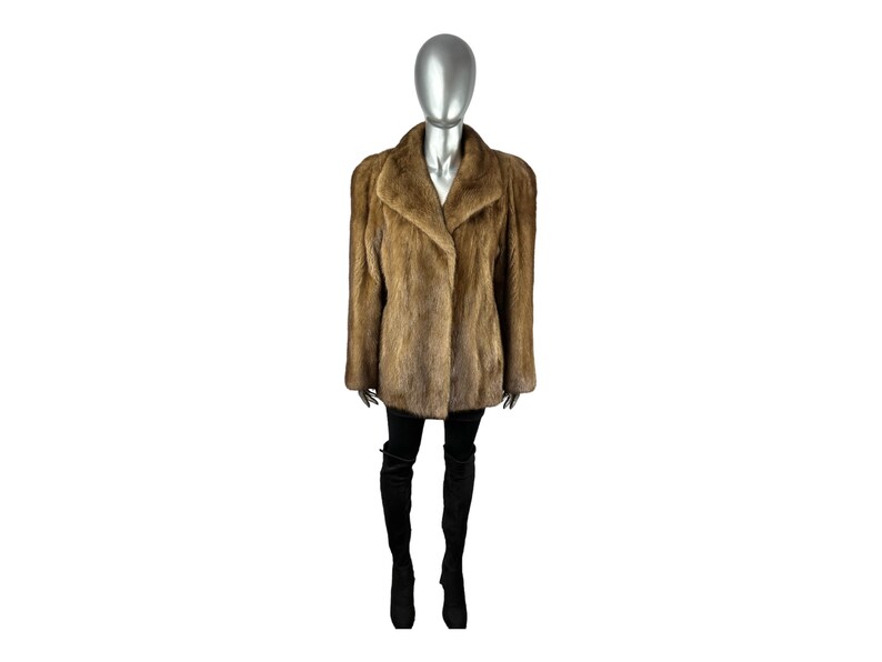 May include: A brown fur coat with a collar and a long sleeve. The coat is being worn by a mannequin.