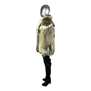 May include: A multi-toned fur coat with a cream-colored collar and a textured pattern. The coat is displayed on a mannequin, showcasing its design and texture. The coat is paired with black thigh-high boots.