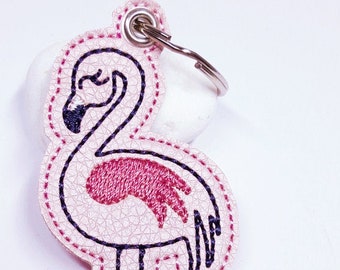 May include: Pink flamingo keyring with a stitched design. The flamingo has a dark pink body and black legs and beak. The keyring includes a metal ring and the text "HIMBEER DESIGN".