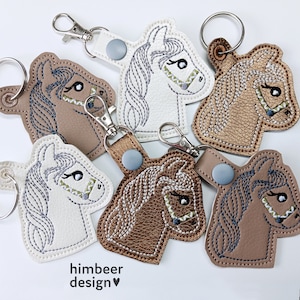 Puede incluir: Cinco llaveros diferentes con forma de cabeza de caballo, cada uno con un color y diseño diferente. Los llaveros están hechos de fieltro y tienen un diseño cosido. Los llaveros están todos unidos a anillos de metal.
