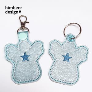 May include: Two light blue angel-shaped keyrings with a blue star in the centre. The keyring on the left has a silver split ring and a light blue swivel clip. The keyring on the right has a silver split ring.