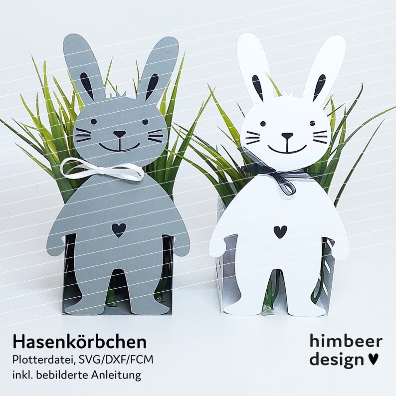 May include: Two bunny-shaped planters, one gray and one white, with black eyes and a black bow. Each planter has a small heart on the front. The planters are filled with green grass.