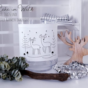 May include: A clear glass candle holder with a black and white illustration of two deer in a snowy forest. The text "Rehe im Wald 13x18, 16x26 UND 18x30ER RAHMEN INKLUSIVE" is printed on the holder.