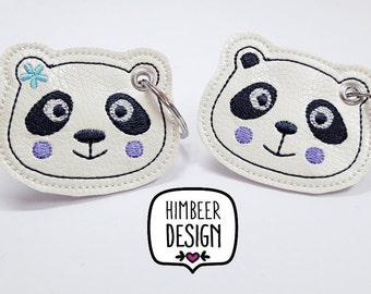 May include: Two white panda bear keychains with black eyes and purple cheeks. The keychain on the left has a blue flower on its head. The keychains are on a white background with the text "Himbeer Design" in black.