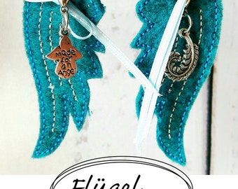 May include: Two teal blue felt angel wings with silver keychains. One keychain has a charm that says "Made for an Angel" and the other has a feather charm. The wings are tied together with a white ribbon.