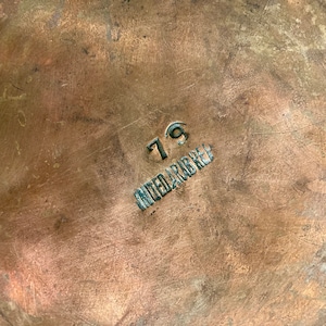 May include: Close-up of a copper-coloured surface with the number "79" and the words "United Arab Rep" stamped in black.