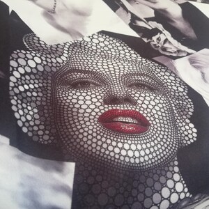 May include: A black and white fabric with a pattern of circles forming a face with red lips. The fabric has the word "Lovely" printed on the bottom right corner.