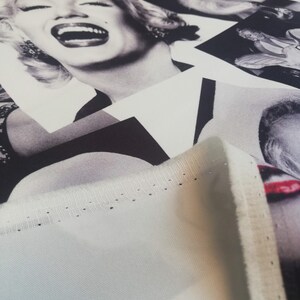 May include: A close-up of a white fabric with a black and white print of a woman's face. The fabric has a stitched edge and the word "Lovely" is printed in the bottom right corner.