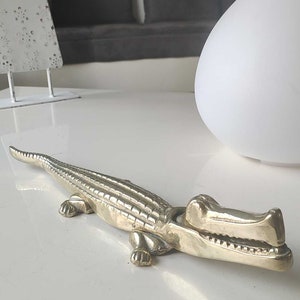 May include: A silver-coloured alligator nutcracker with a detailed textured body and open mouth.